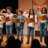 Kinder lesen mit Mimik und Gestik Rollen auf der Bühne – Barbara Raths Vorlesetheater stärkt Lesefluss, Textverständnis und Lesemotivation im Unterricht 📚✨ Kinder auf einer Schulbühne lesen dialogisch aus Büchern und begleiten ihre Rollen mit Gesten – Vorlesetheater von Barbara Rath beim BVK fördert nachhaltige Lesekompetenz und macht Spaß 🧒👧🎓🎬